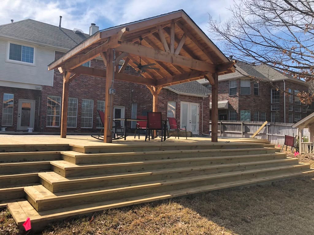 Custom cedar covered patio pavilion with wide wood steps built by Horseshoe Landscaping and Construction in the Dallas-Fort Worth area